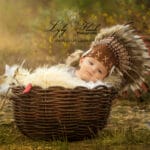 un bébé dans un beau panier en osier avec une coiffe d indien près de Évenos pour son shooting photo bébé