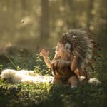 Petite fille dans la foret qui croise un petit papillon. Elle porte une tunique d indienne et une grande toque près de Cabasse